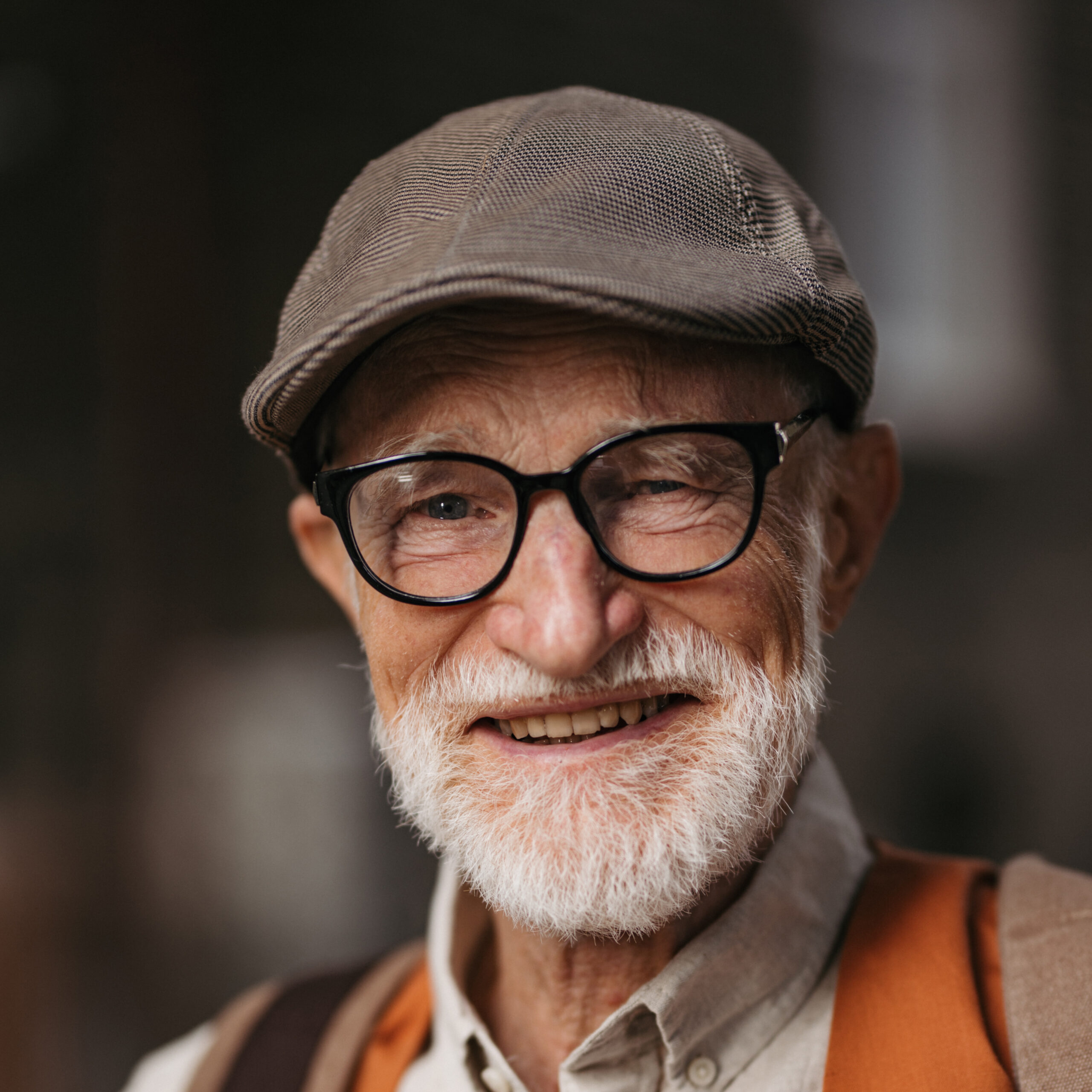 Studio portrait of a senior man with glasses and a beret on his head. Handsome smiling elderly man.